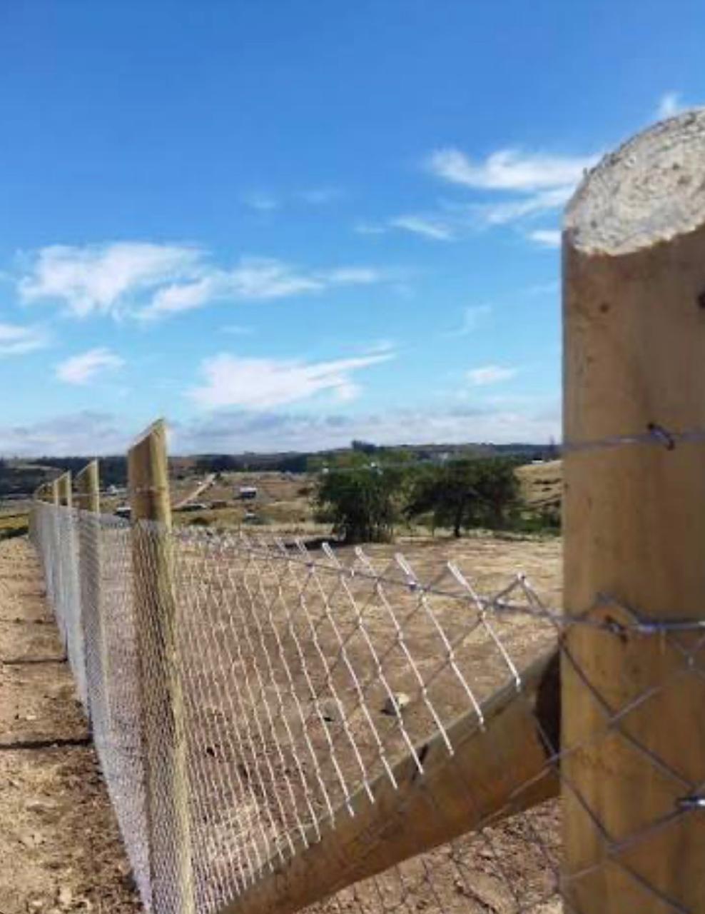 Cierre de malla con postes de madera y alambre de púas